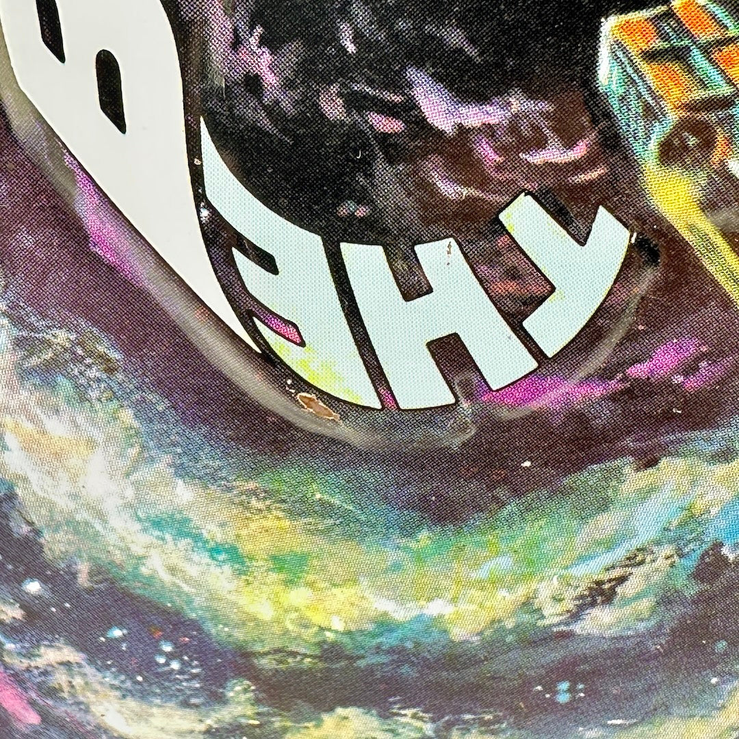 Close-up of a graphic print featuring stylized white text over a psychedelic space scene with swirling colors.