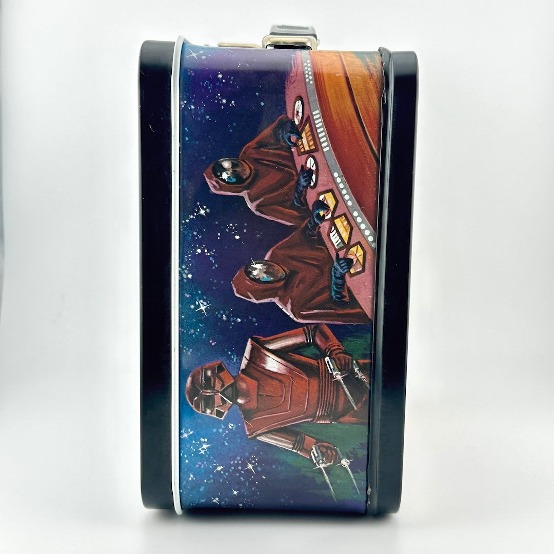 A rectangular metal lunchbox with a dark blue and brown sci-fi space illustration, shown on a white background.