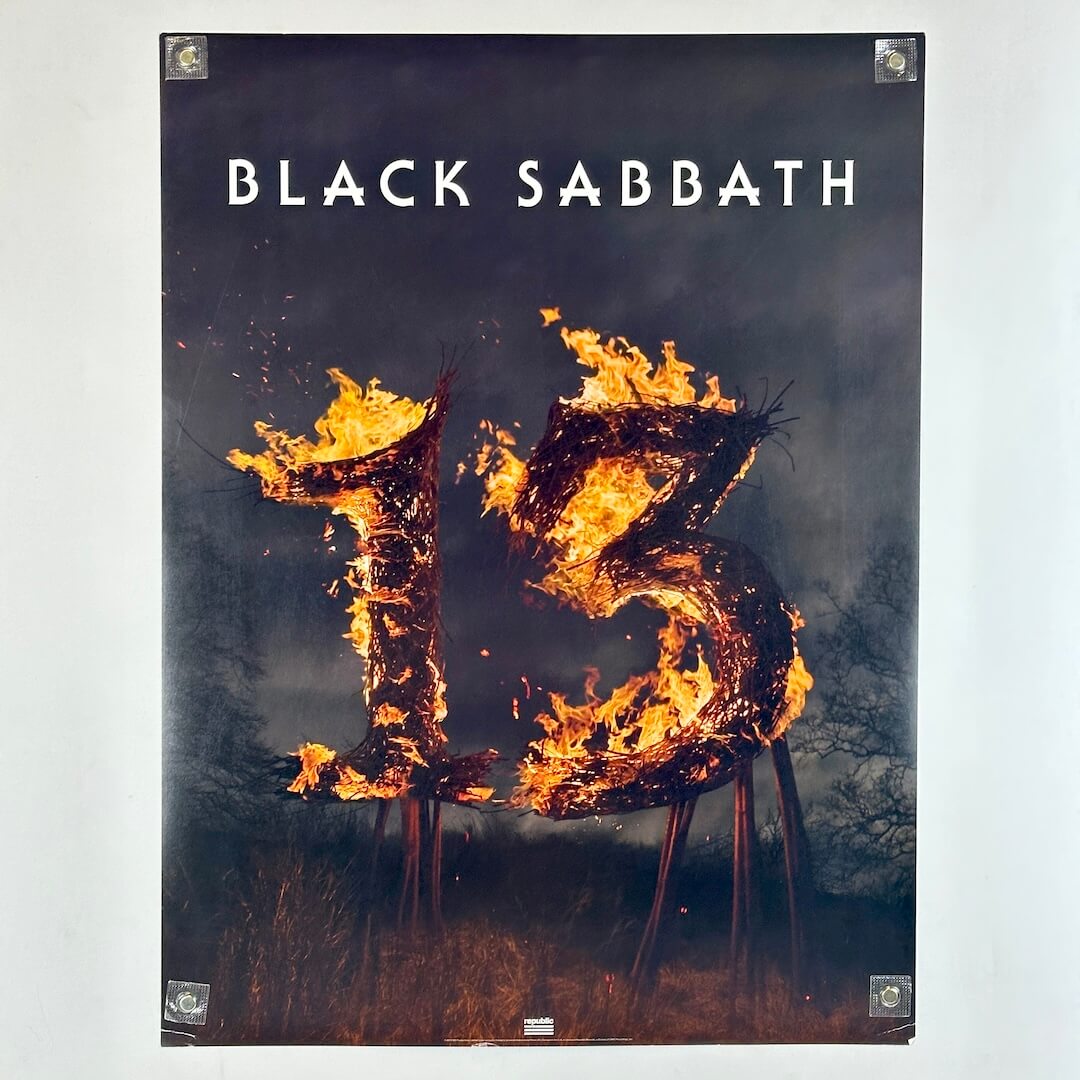 Black Sabbath poster with flaming "13". in center with brush around it. 