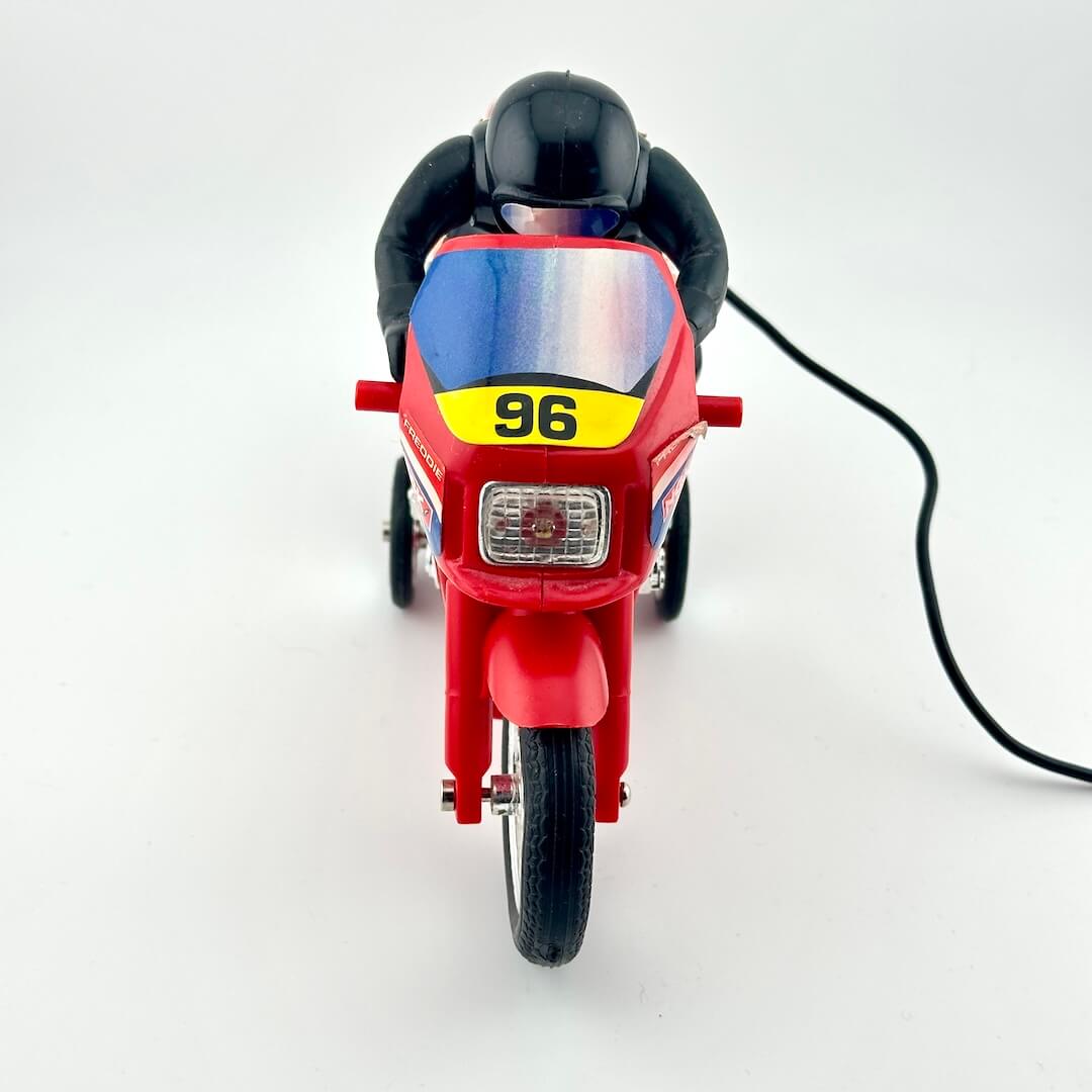 A red toy motorcycle with a black rider figure, photographed from the front on a plain white studio background.