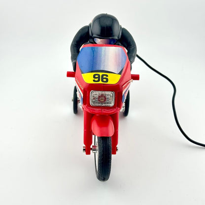 A red toy motorcycle with a black rider figure, photographed from the front on a plain white studio background.