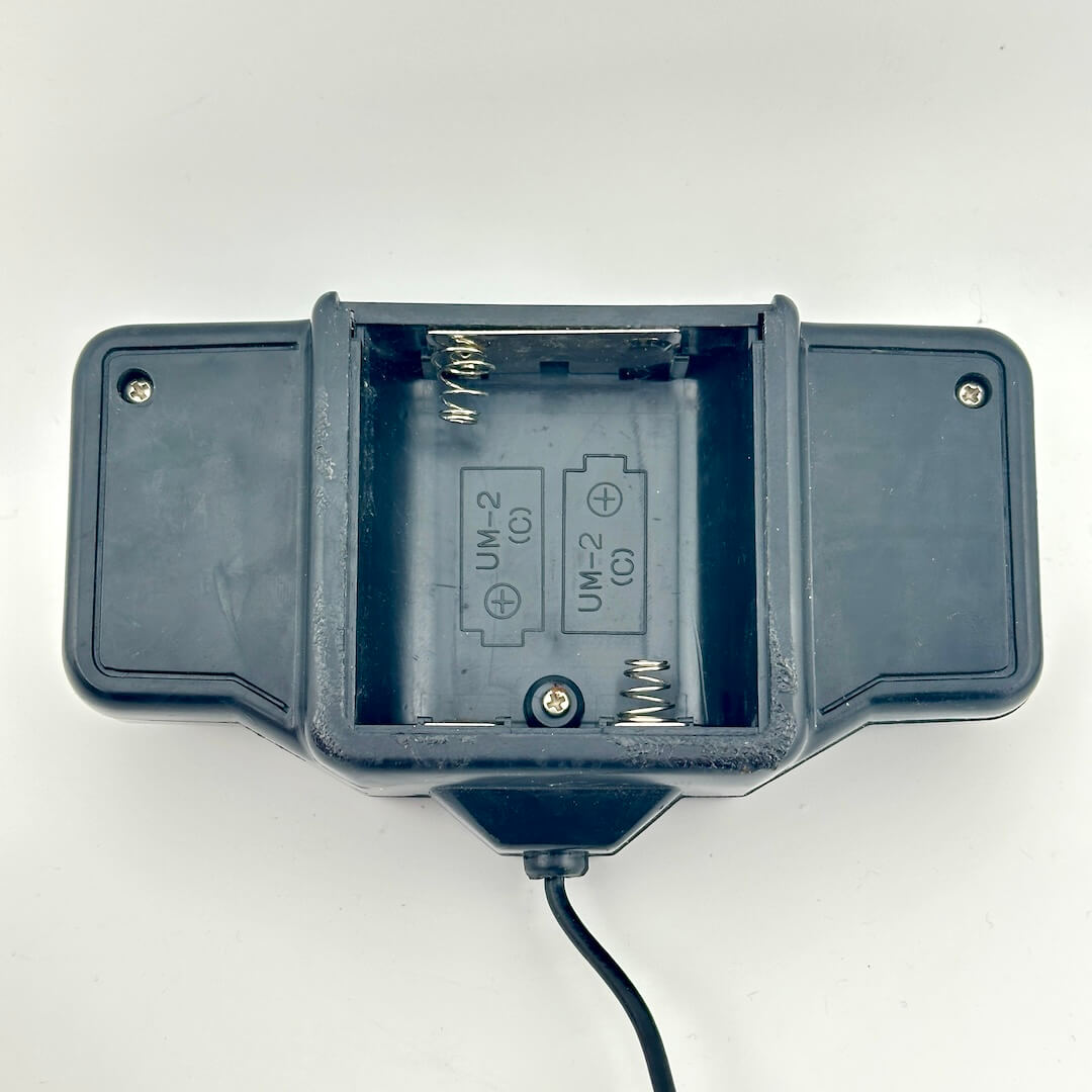 Black remote control with battery compartment visible with no corrosion. 