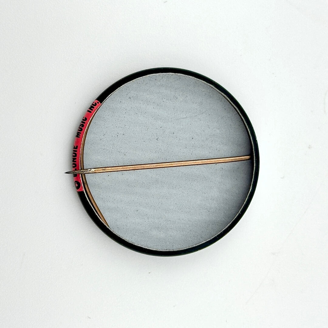 Round metallic object with a central rod on a white background