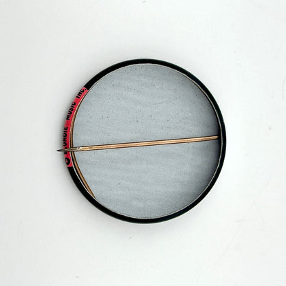 Round metallic object with a central rod on a white background