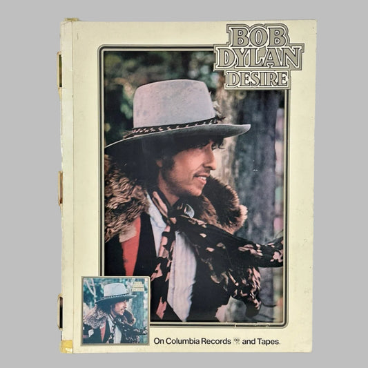 White rectangular sign with BOB DYLAN printed at top, color picture of Dylan in center, mini album cover at bottom.