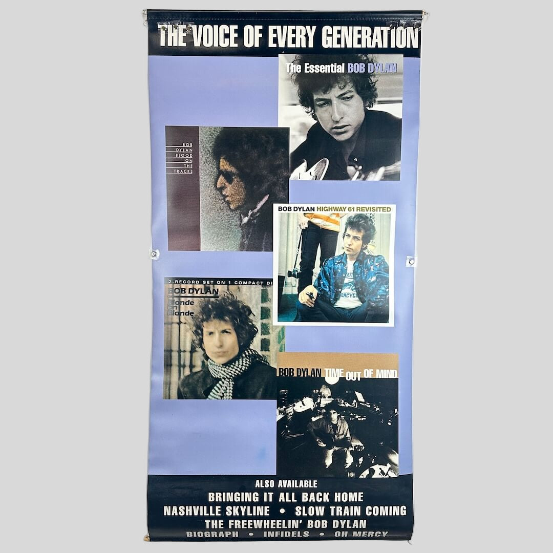 Bob Dylan album cover poster with images and text on a white wall.