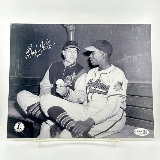 Two baseball players sitting on a bench with a signature above them, framed by a white border.