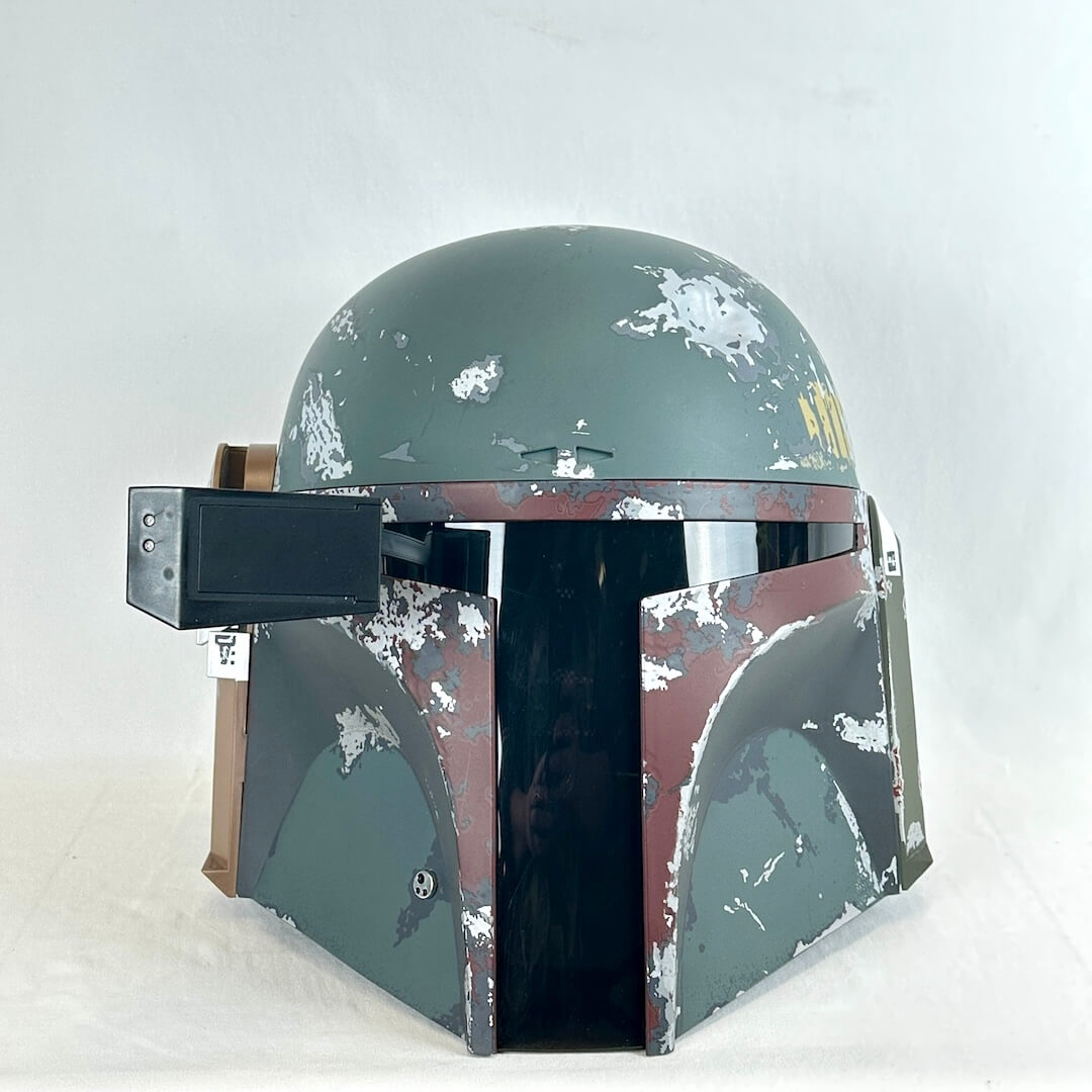 A distressed Boba Fett style helmet replica, featuring a weathered green-gray and brown paint scheme.