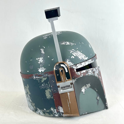 A Boba Fett style helmet replica with a distressed green matte finish, brown and red markings, and a silver visor arm.