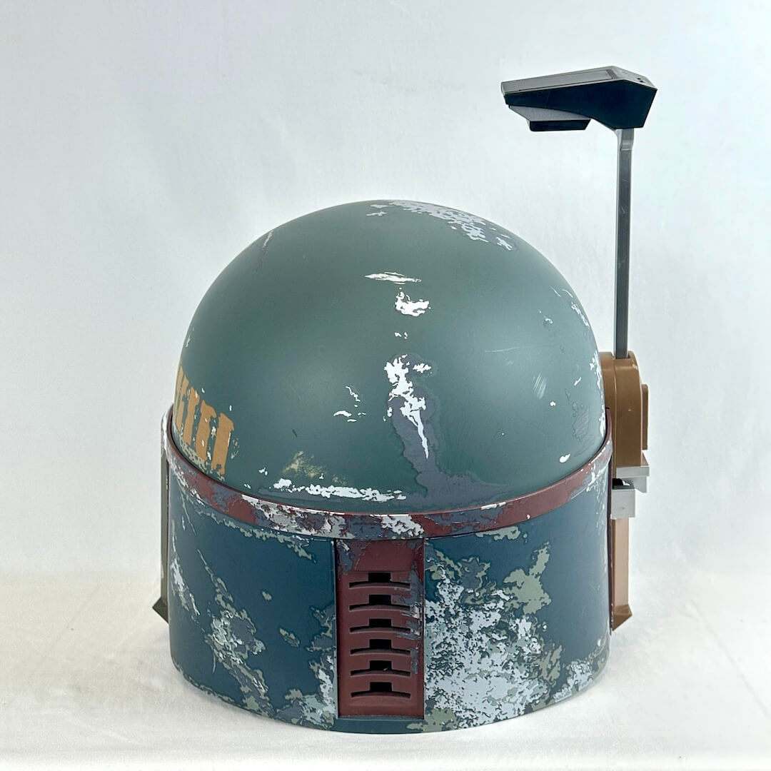 A distressed Boba Fett style sci-fi helmet replica, featuring a weathered green-gray dome, and rust-red band.