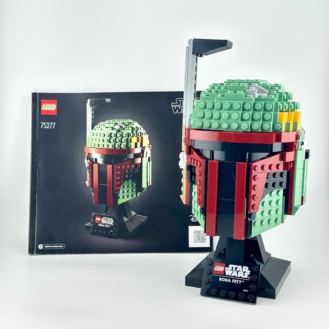 Lego bust of Boba Fett with instruction booklet against white background.
