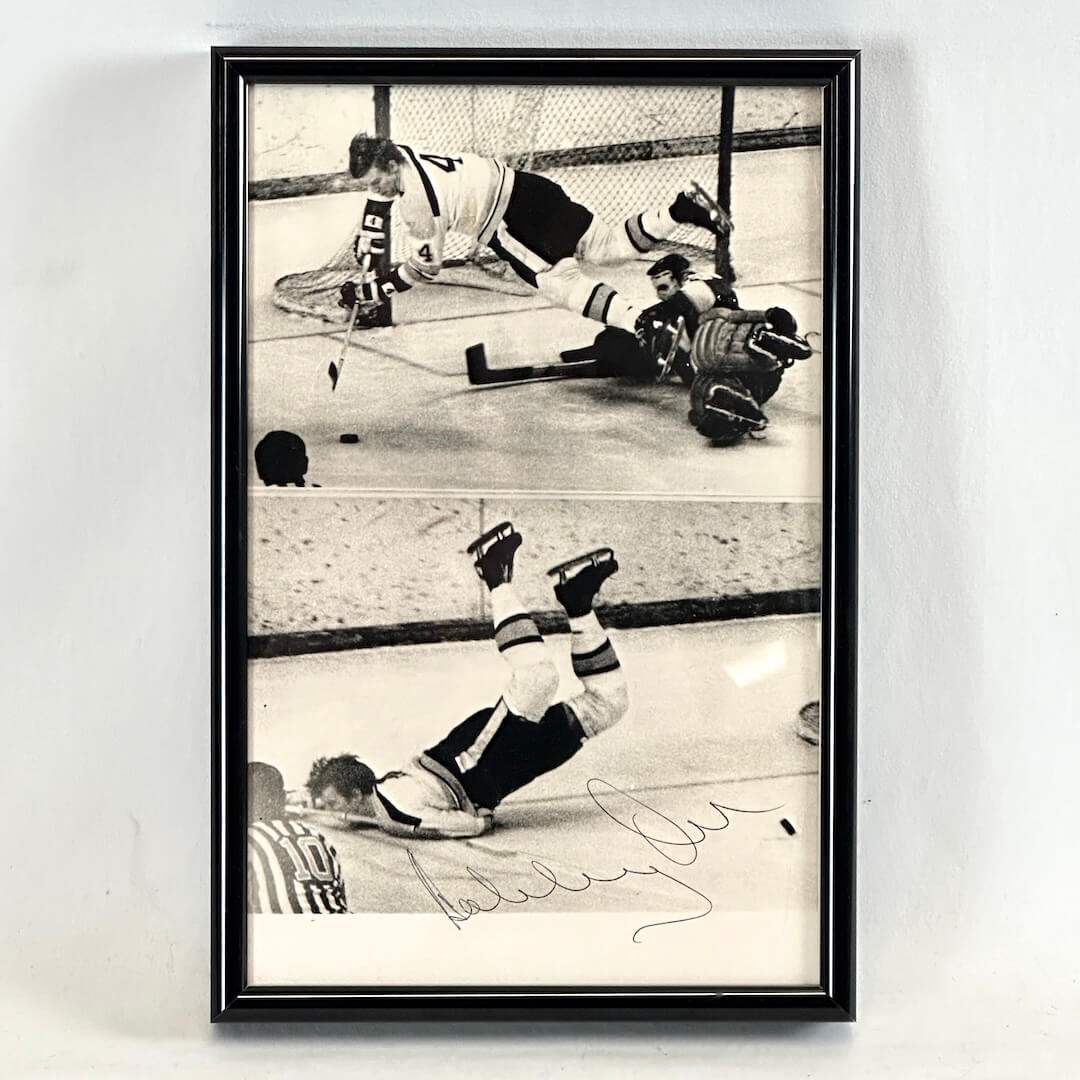 Black framed black and white images of hockey players with signature, photographed on white background. 