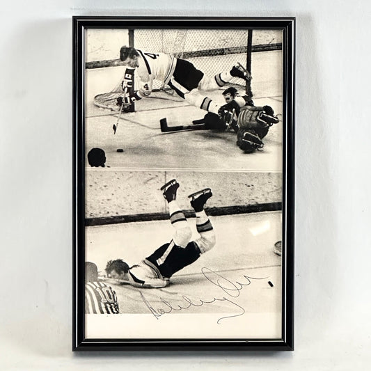 Black framed black and white images of hockey players with signature, photographed on white background. 