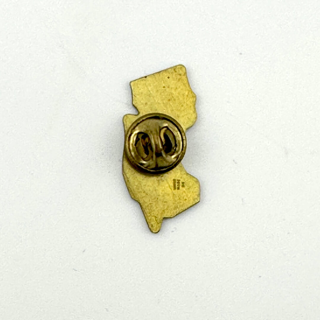 Gold-colored pin in the shape of a stylized map on a white background