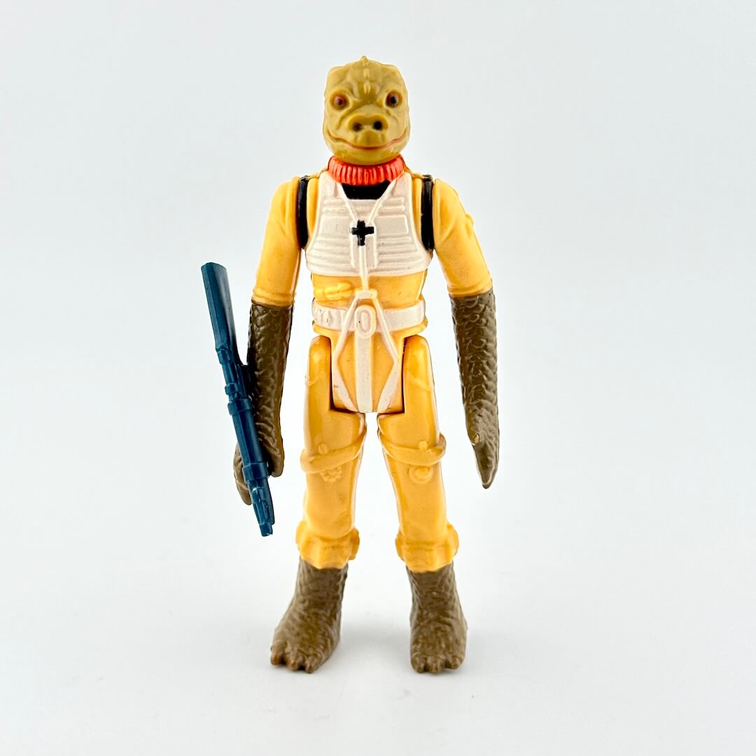 Alien action figure in yellow suit with white accents with weapon on white background. 