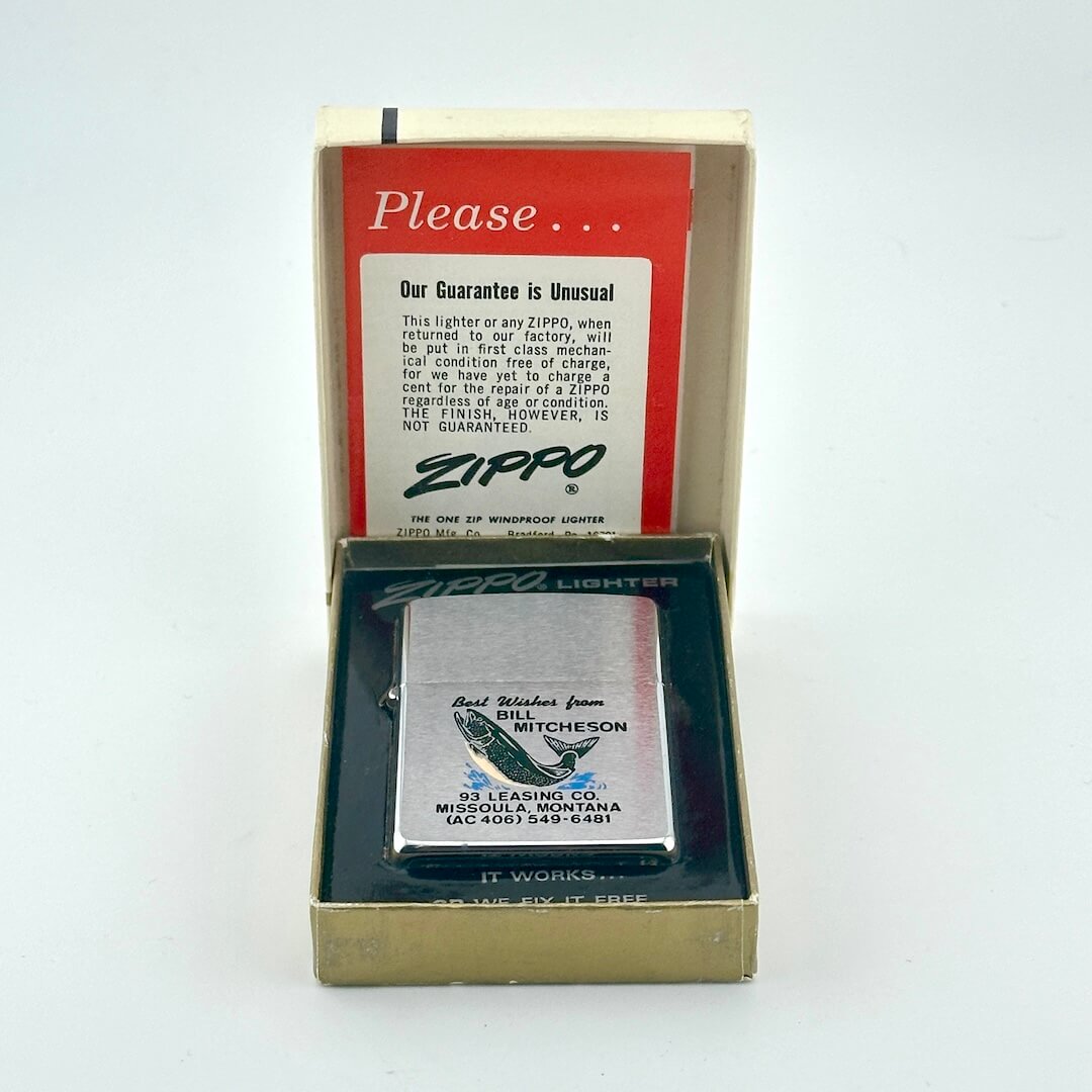 A vintage Zippo novelty lighter displayed in an open gold-colored presentation box, with the branded inner card. 