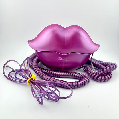 A metallic purple lip-shaped phone with a matching coiled cord, photographed on a plain light background.