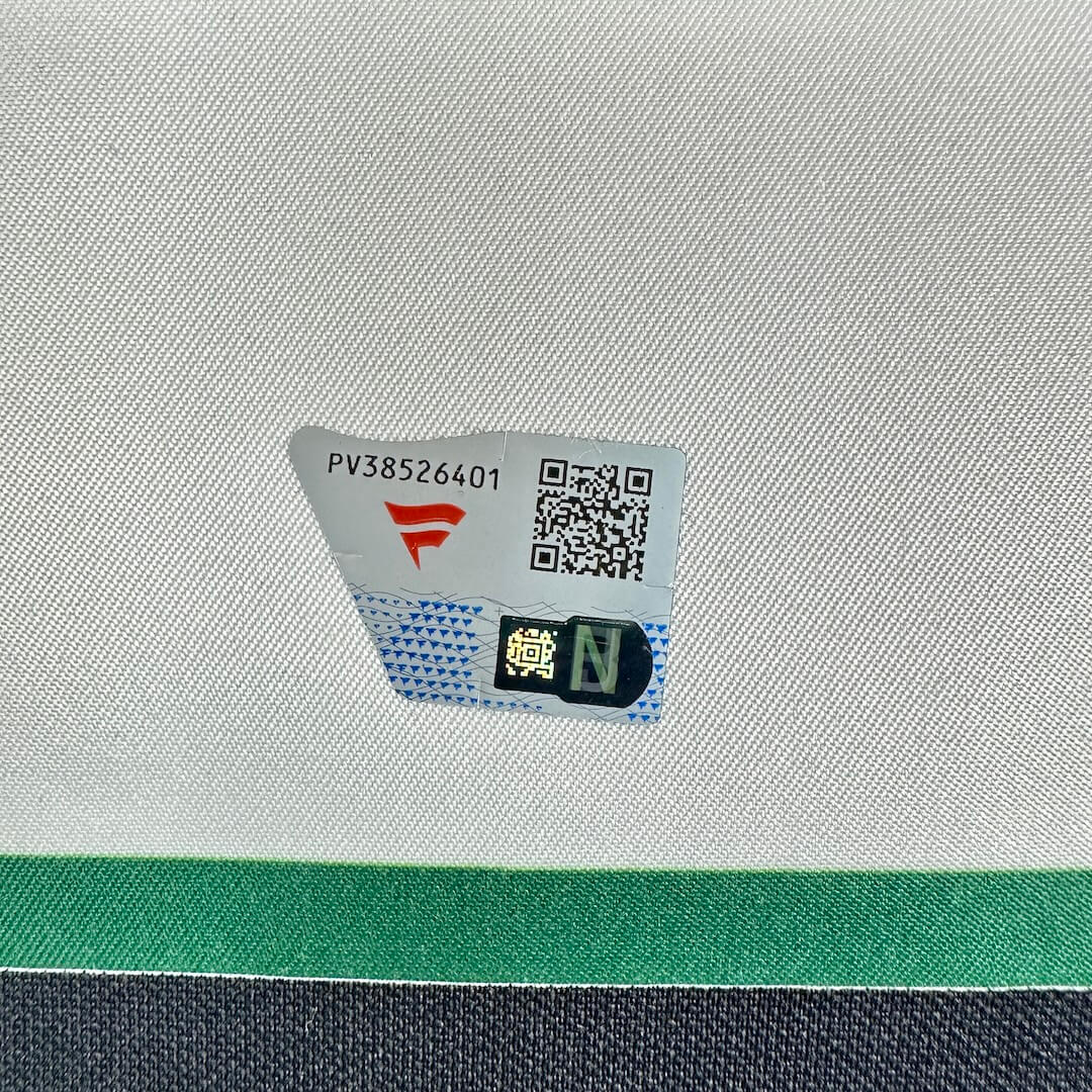 A close-up of a white textured fabric surface with a small printed label showing a red logo, and a QR code.