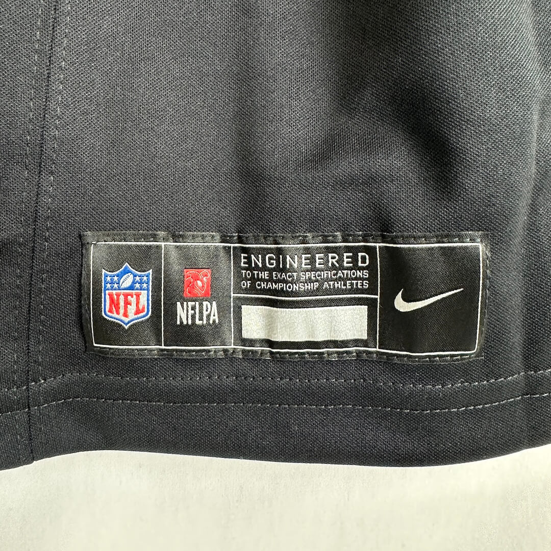 Close-up of a black athletic jersey collar showing an NFL and Nike label with logos and text.