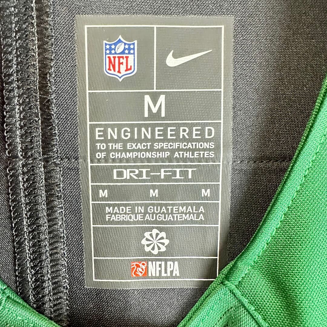 Close-up of a Nike NFL Dri-Fit collar label showing size M, with NFL shield, Nike swoosh, and NFLPA logos.