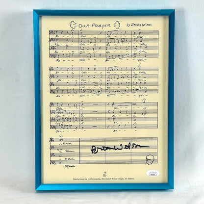 A turquoise framed sheet of music signed by Brian Wilson with authentication sticker at bottom right. 