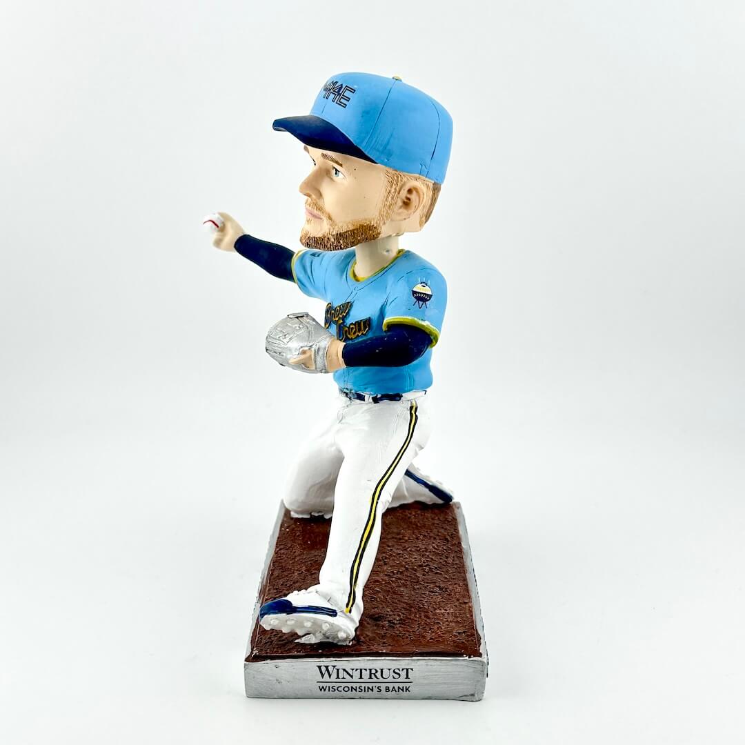 Bobblehead of baseball player in blue uniform throwing a ball against a white background. 