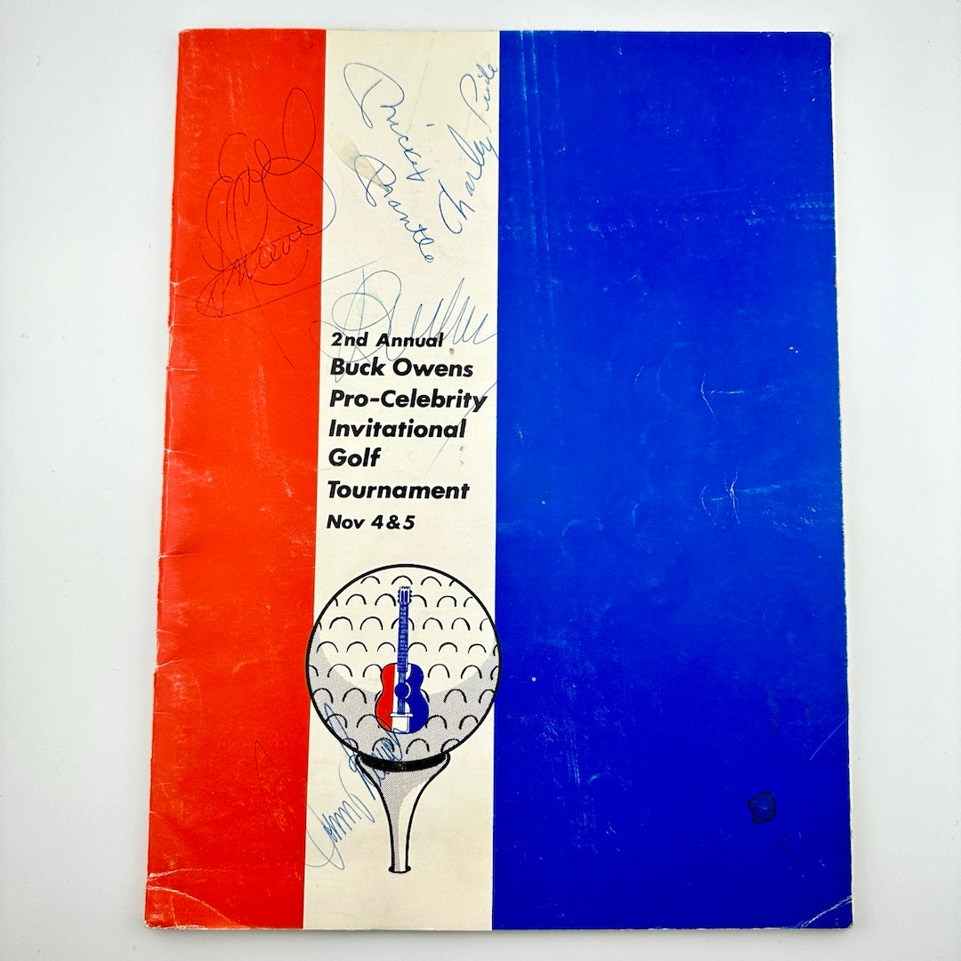 Booklet vertically striped with 3 thick red, white & blue, a white golf ball on tee under event info in black & blue ink signatures.