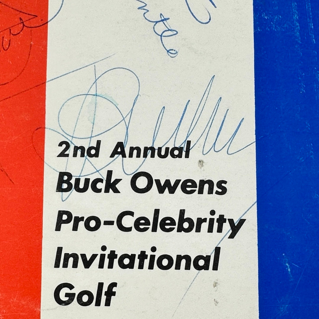 Close-up of Buck Owens' signature in blue ballpoint pen ink over event title.