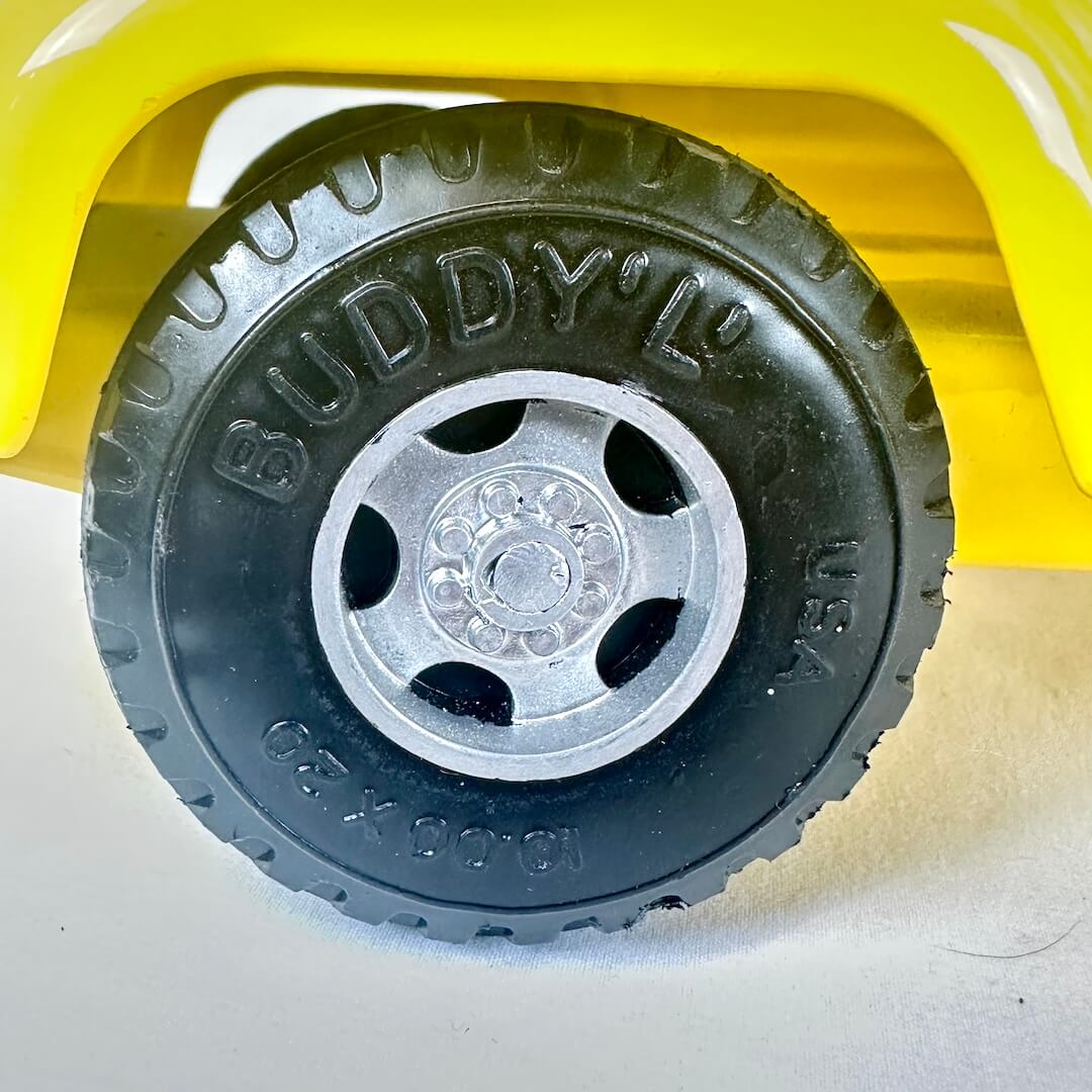 Close-up of a Buddy L toy truck tire with yellow body and black tire.