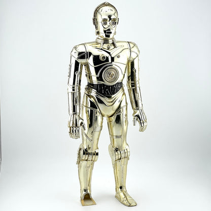 Plastic figure of gold/silver robot with broken left foot against white background. 