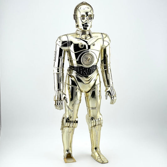 Plastic figure of gold/silver robot with broken left foot against white background. 