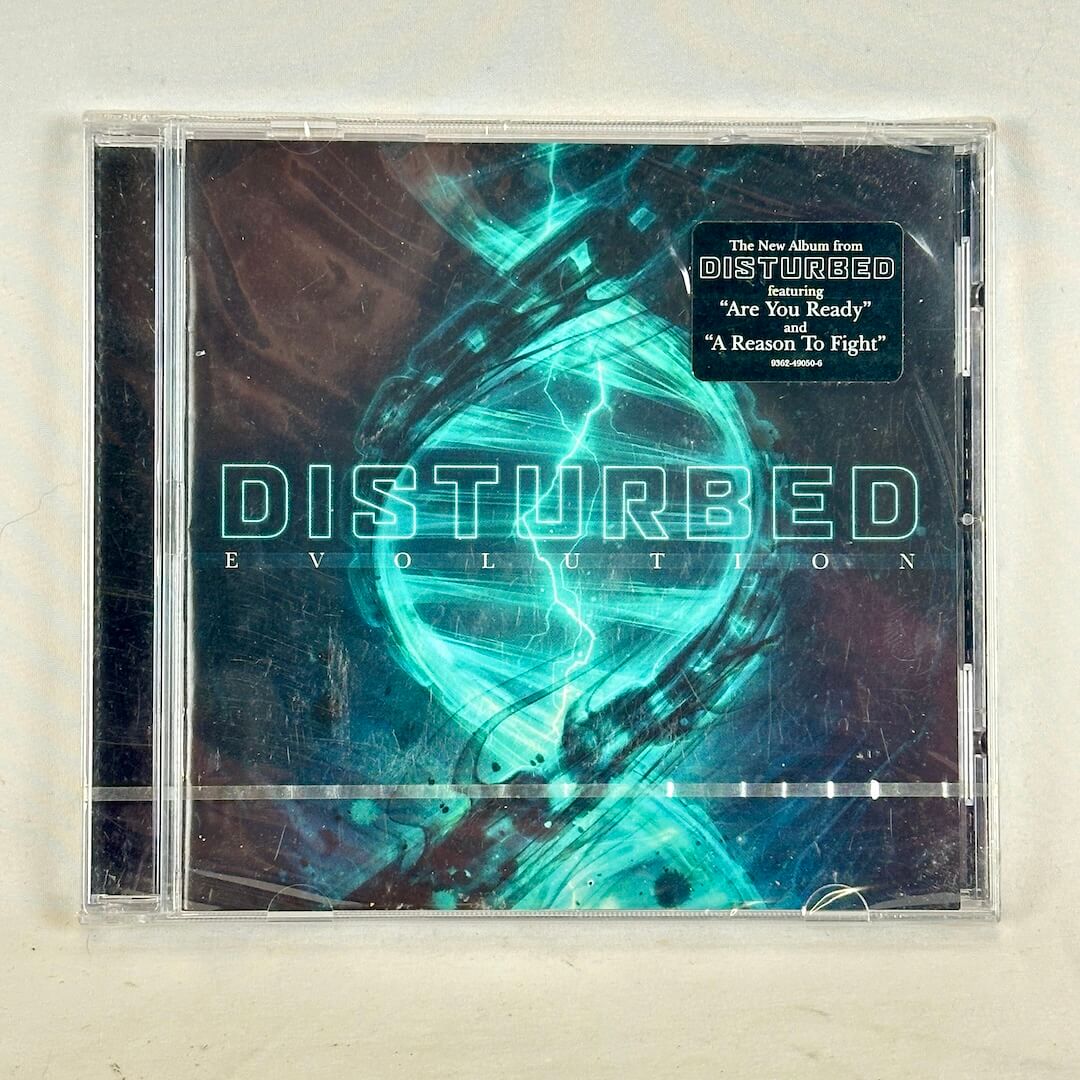 CD cover of Disturbed's 'Evolution' with abstract design and text.