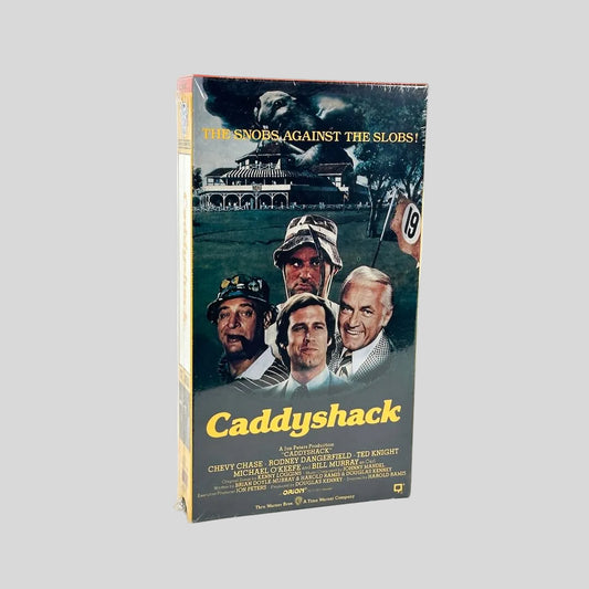 Sealed Caddyshack VHS with actors on front below building, against white background.