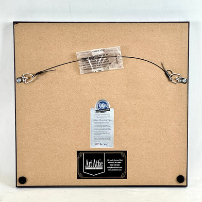 Backside of frame showing framer and care information, photographed against light background. 