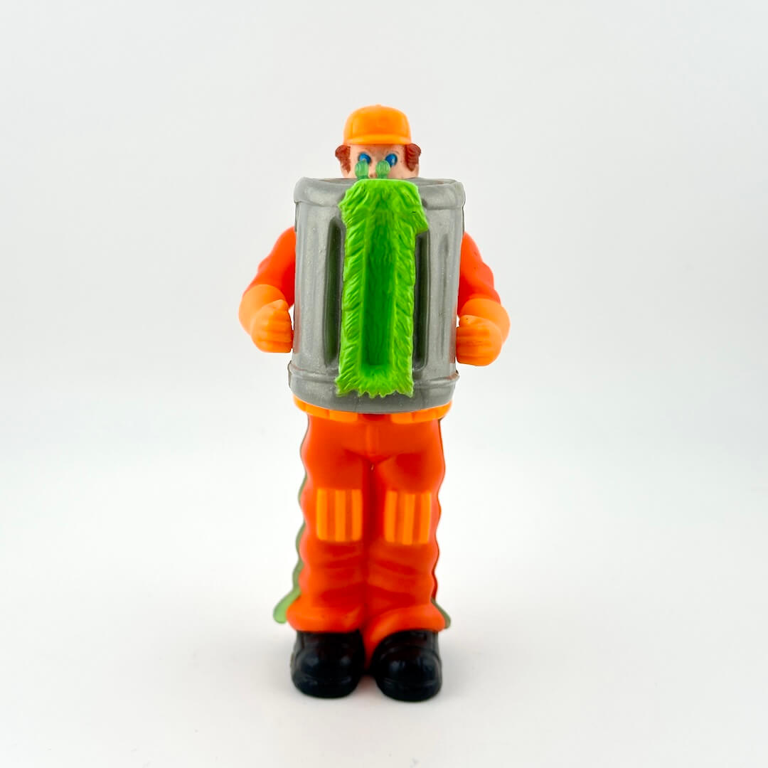 Toy figure in orange jumpsuit with a green broom-like object on a white background