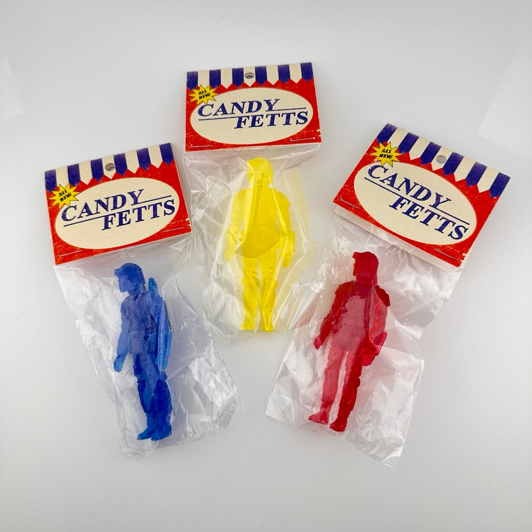 Three semi-transparent figures, one each of blue, yellow, & red in their plastic packaging. 