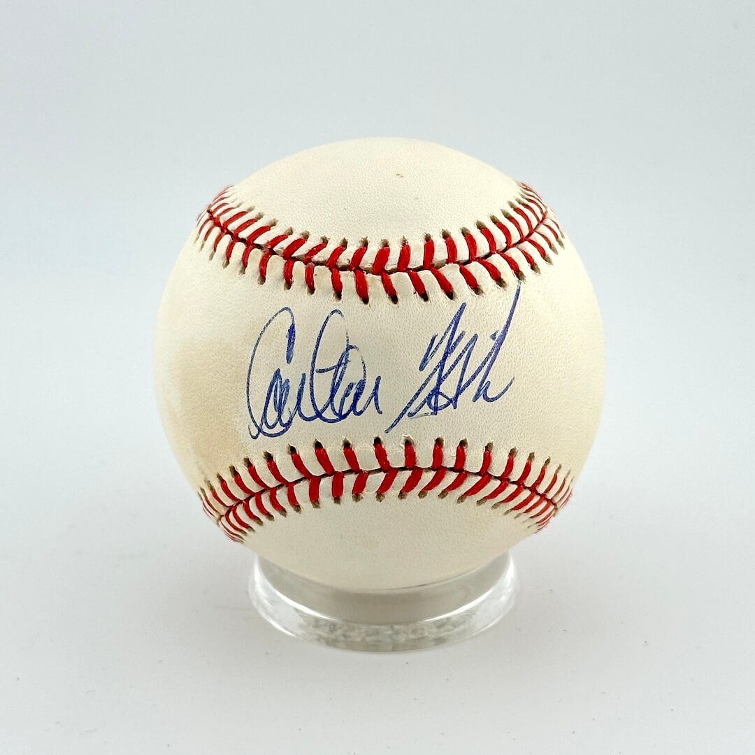 Baseball with autograph on a clear stand against a light gray background