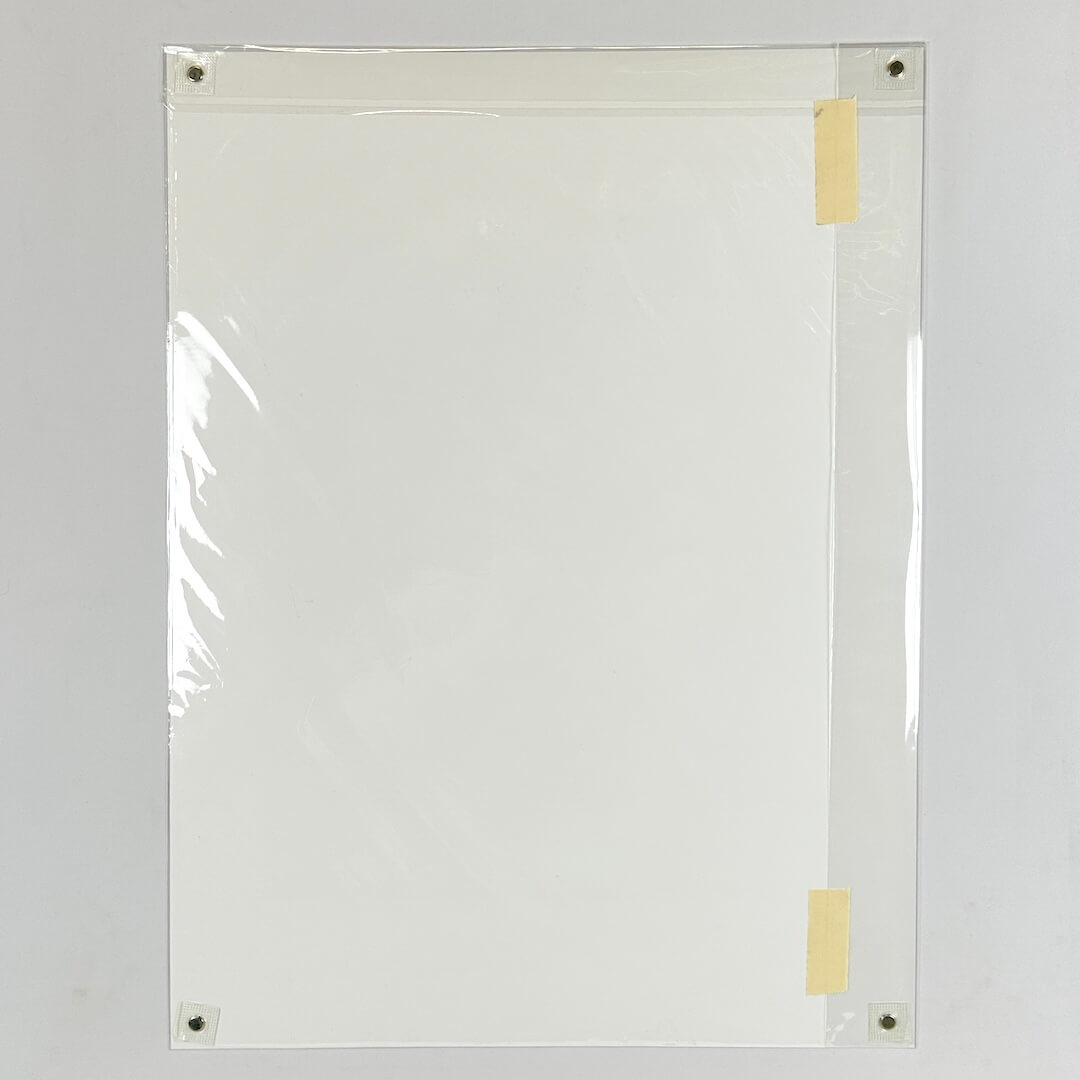 Backside of print showing plain white poster on white background, with pieces of tape on the outer plastic layer. 