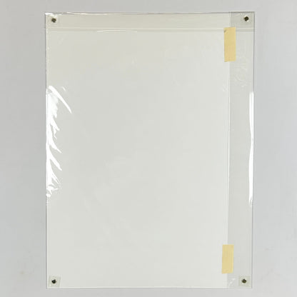 Backside of print showing plain white poster on white background, with pieces of tape on the outer plastic layer. 