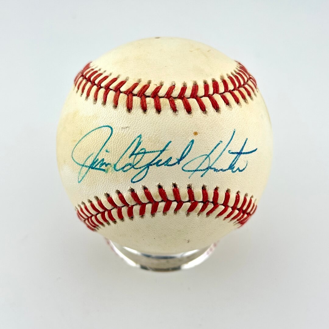 An autographed baseball signed in blue ink displayed on a clear acrylic stand. 