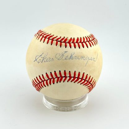 Baseball with red stitching on a clear stand against a white background