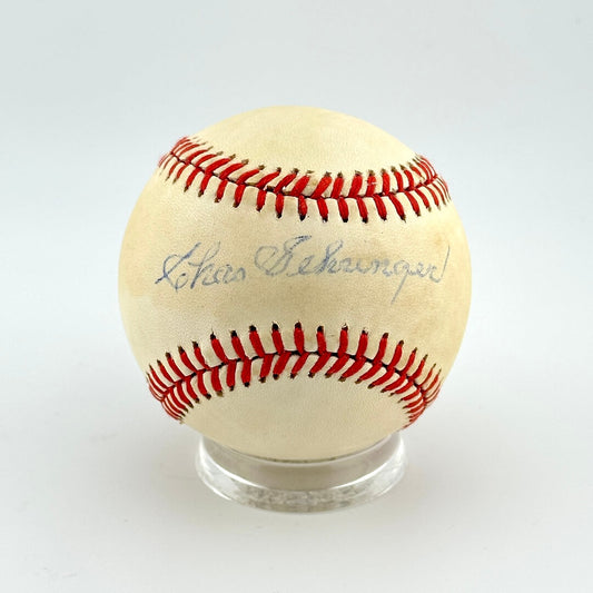 Baseball with red stitching on a clear stand against a white background