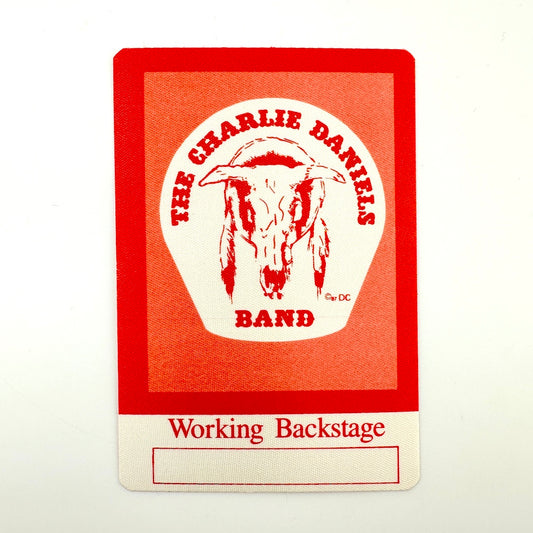 Red and white backstage pass with image of cow skull in center. 