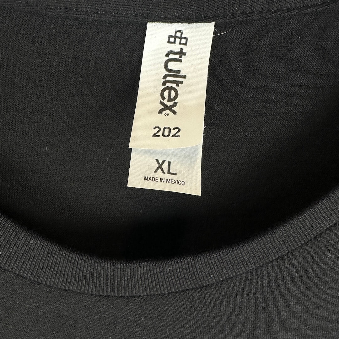 Close-up of a black crewneck shirt showing the inner neck labels, including a Tultex brand tag and a size XL tag.