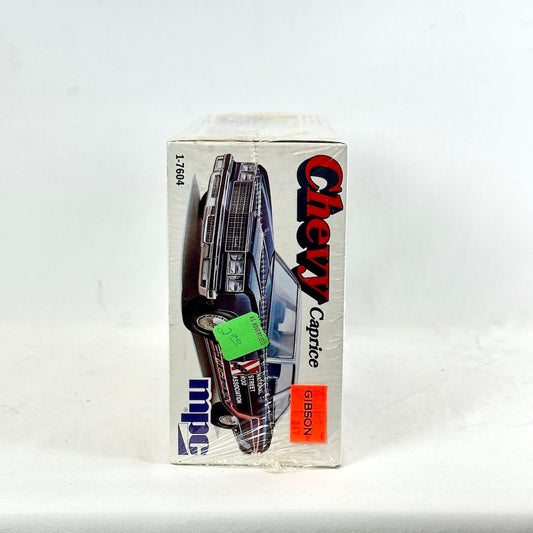 Box with vintage model kit for Chevy Caprice against white background. 