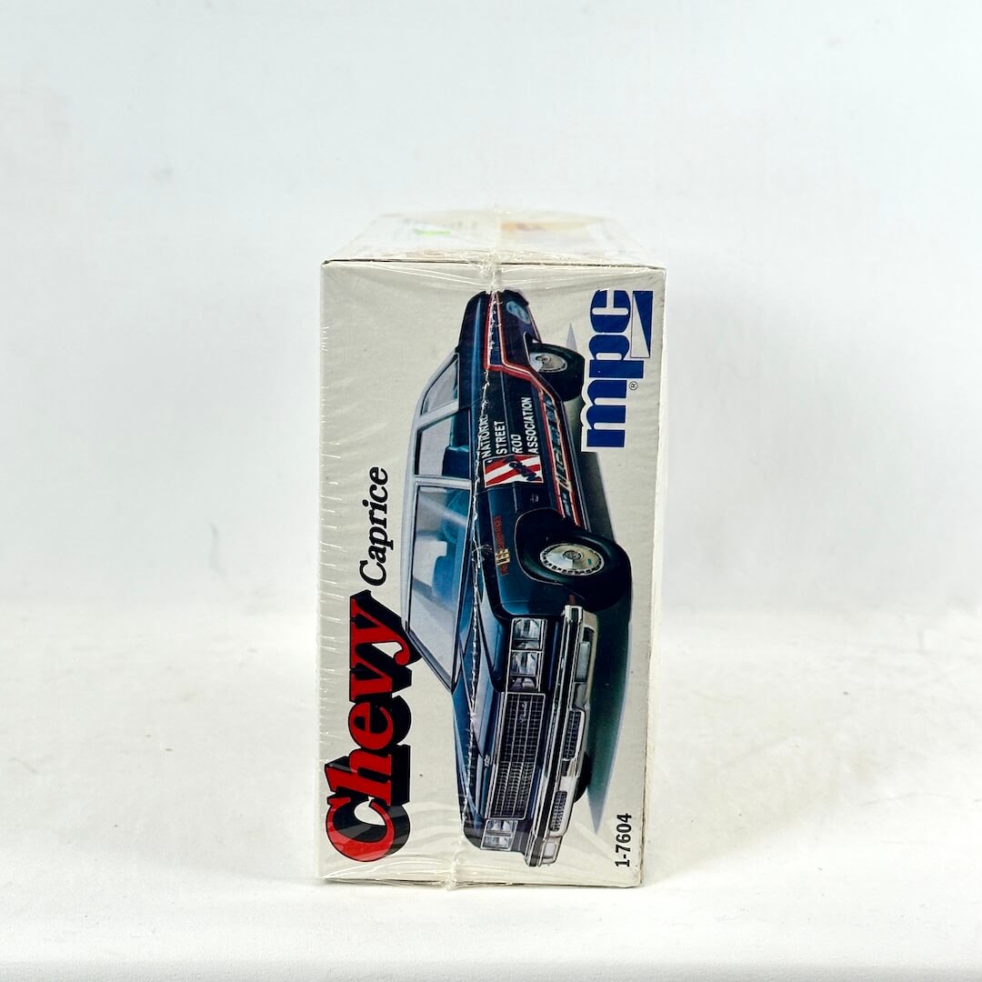 Box with vintage model kit for Chevy Caprice against white background. 