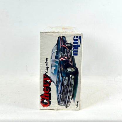 Box with vintage model kit for Chevy Caprice against white background. 