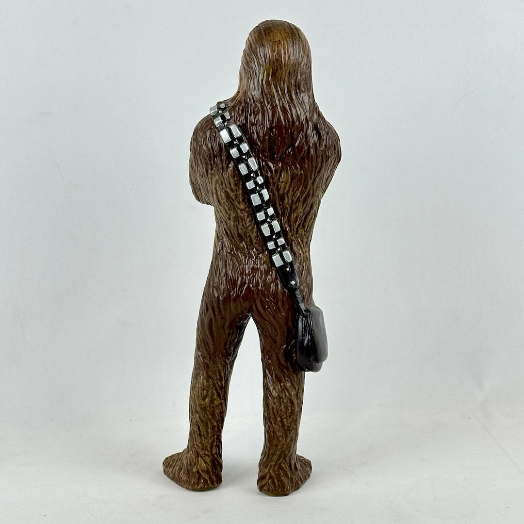 Brown furry creature figure with a black and white striped strapped bag on a white background