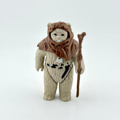 Toy figure of a character in a brown hood and beige outfit with a staff on a white background
