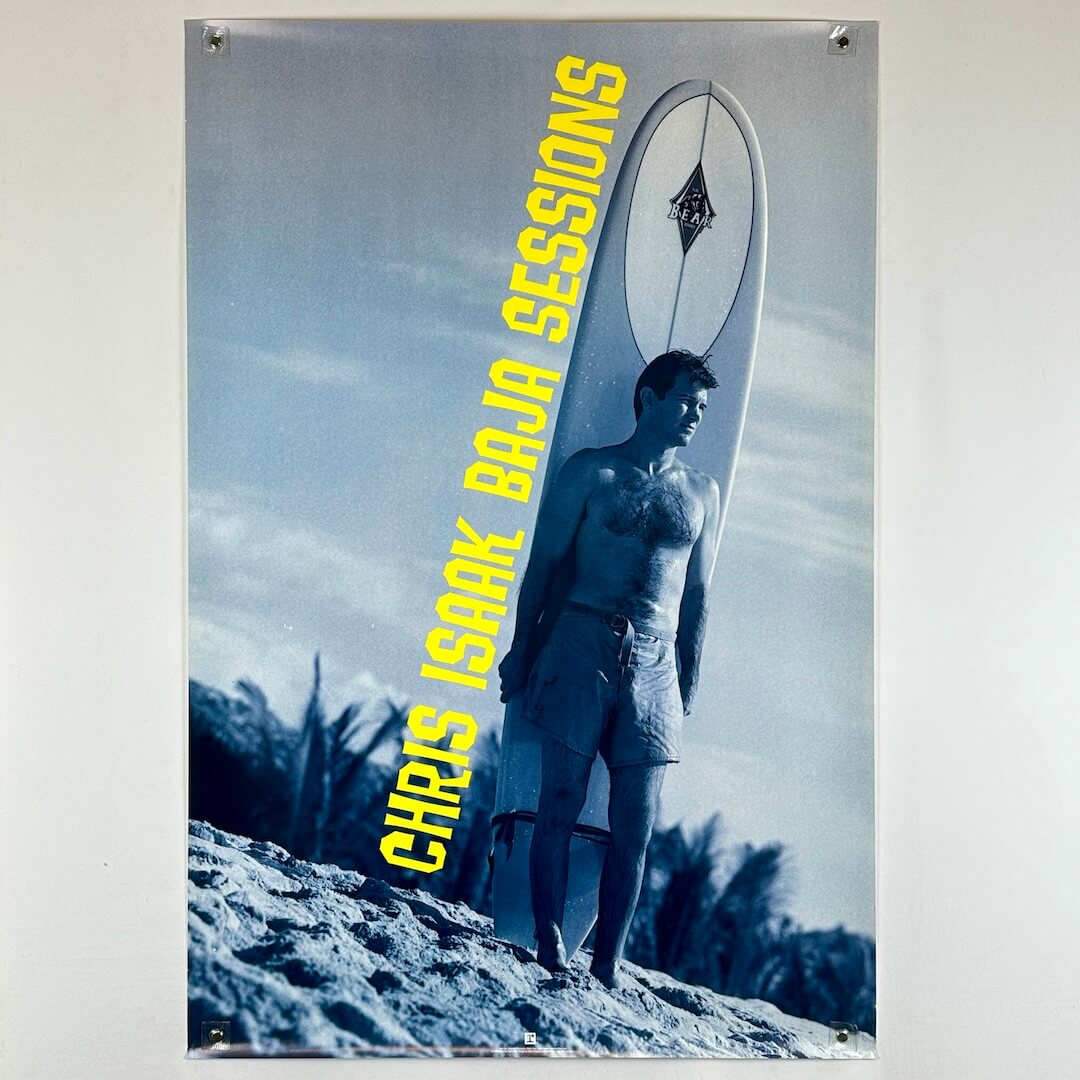 Poster of a man with a surfboard on a beach with 'Chris Isak Baja Sessions' text.